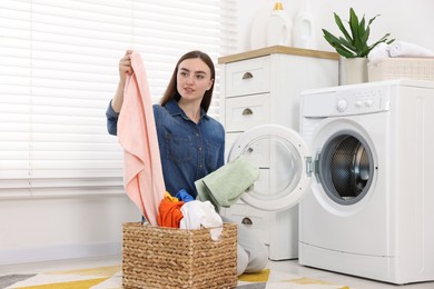 Photo of Woman with laundry near washing machine indoors