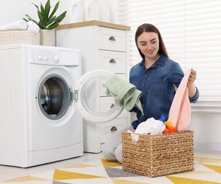 Photo of Woman with laundry near washing machine indoors