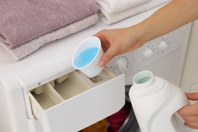 Photo of Woman pouring detergent into washing machine drawer indoors, closeup. Laundry day