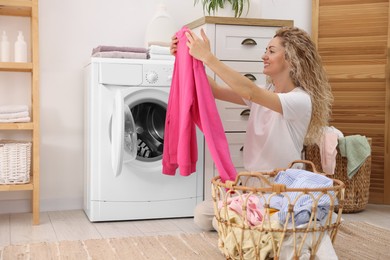 Photo of Woman with laundry near washing machine indoors