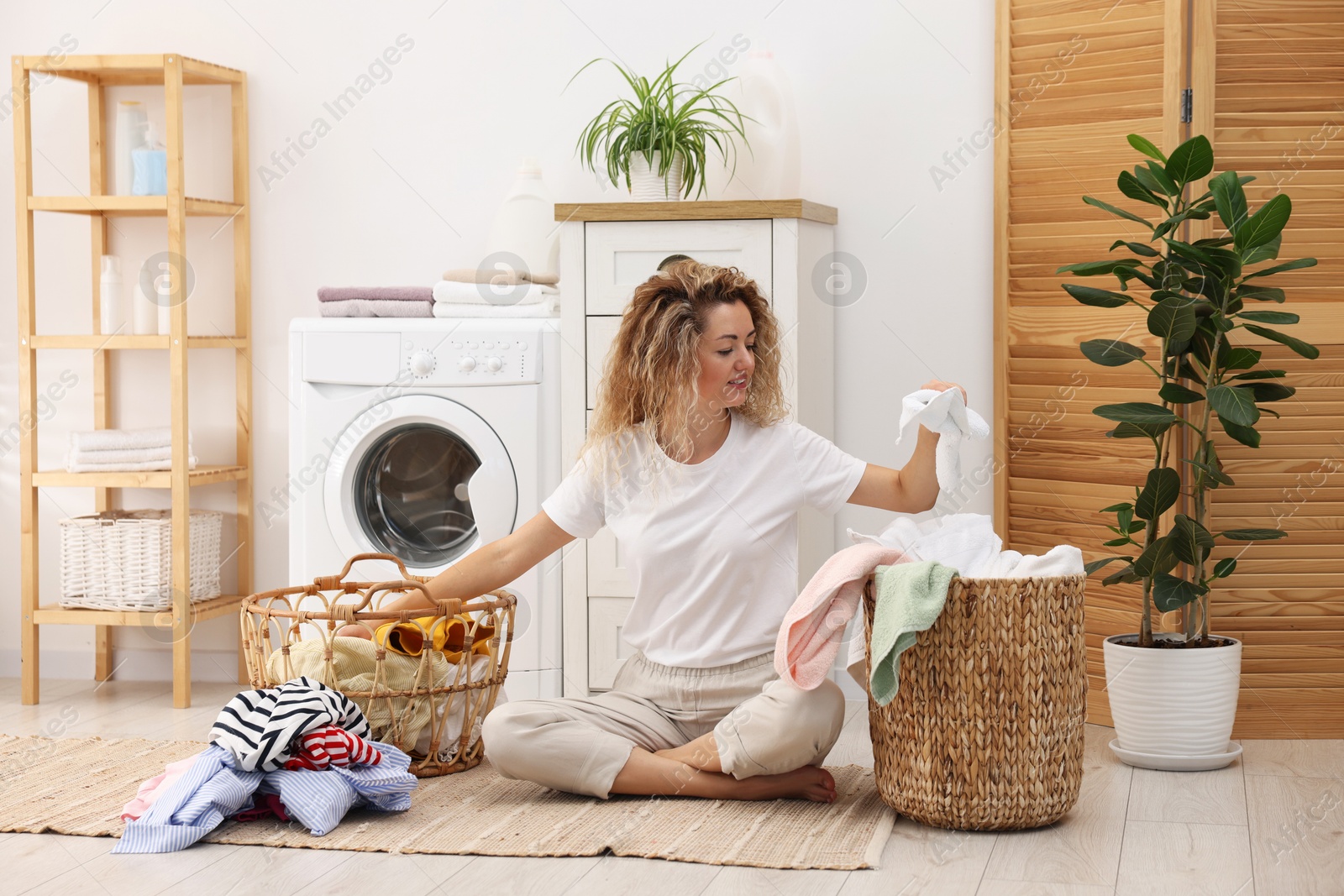 Photo of Woman with laundry near washing machine indoors