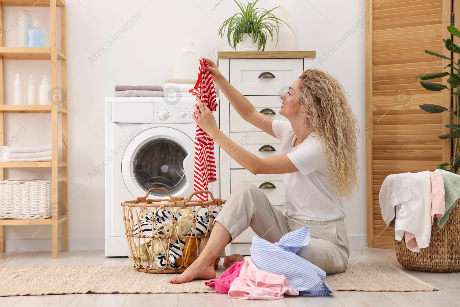 Woman with laundry near washing machine indoors Photo of Woman with laundry near washing machine indoors