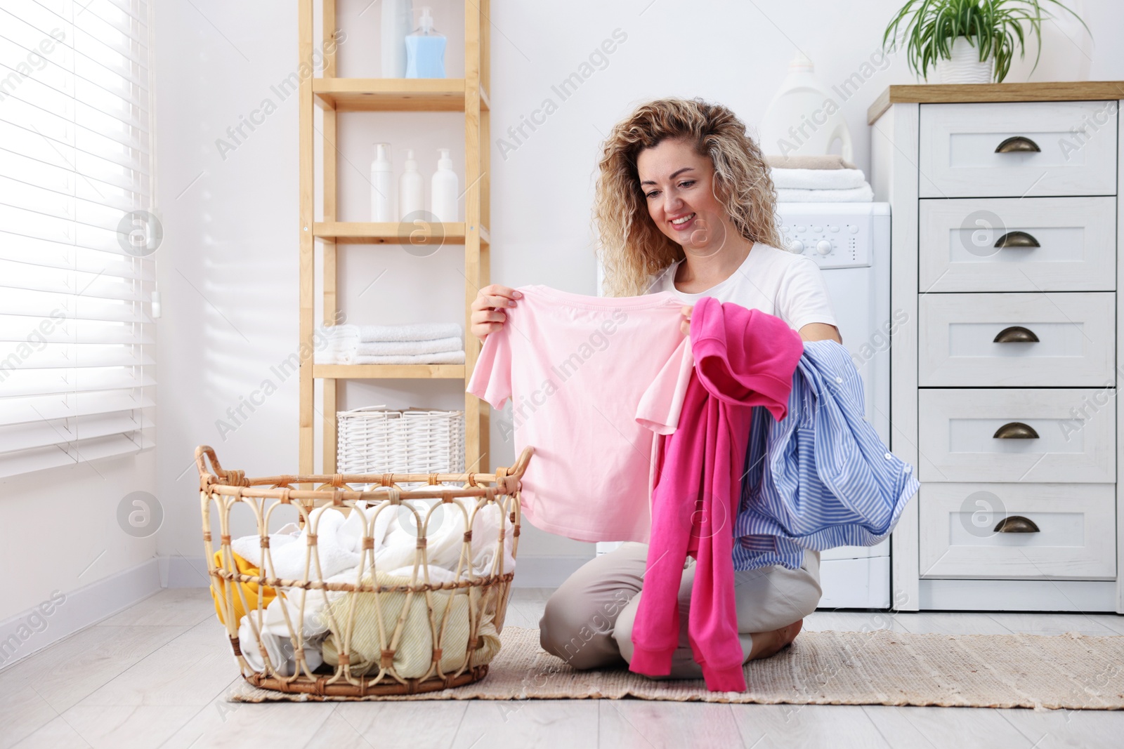 Woman with laundry near washing machine indoors Photo of Woman with laundry near washing machine indoors