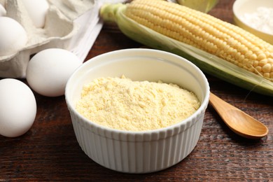 Photo of Different ingredients for corn bread. Corn flour, cob and eggs on wooden table, closeup