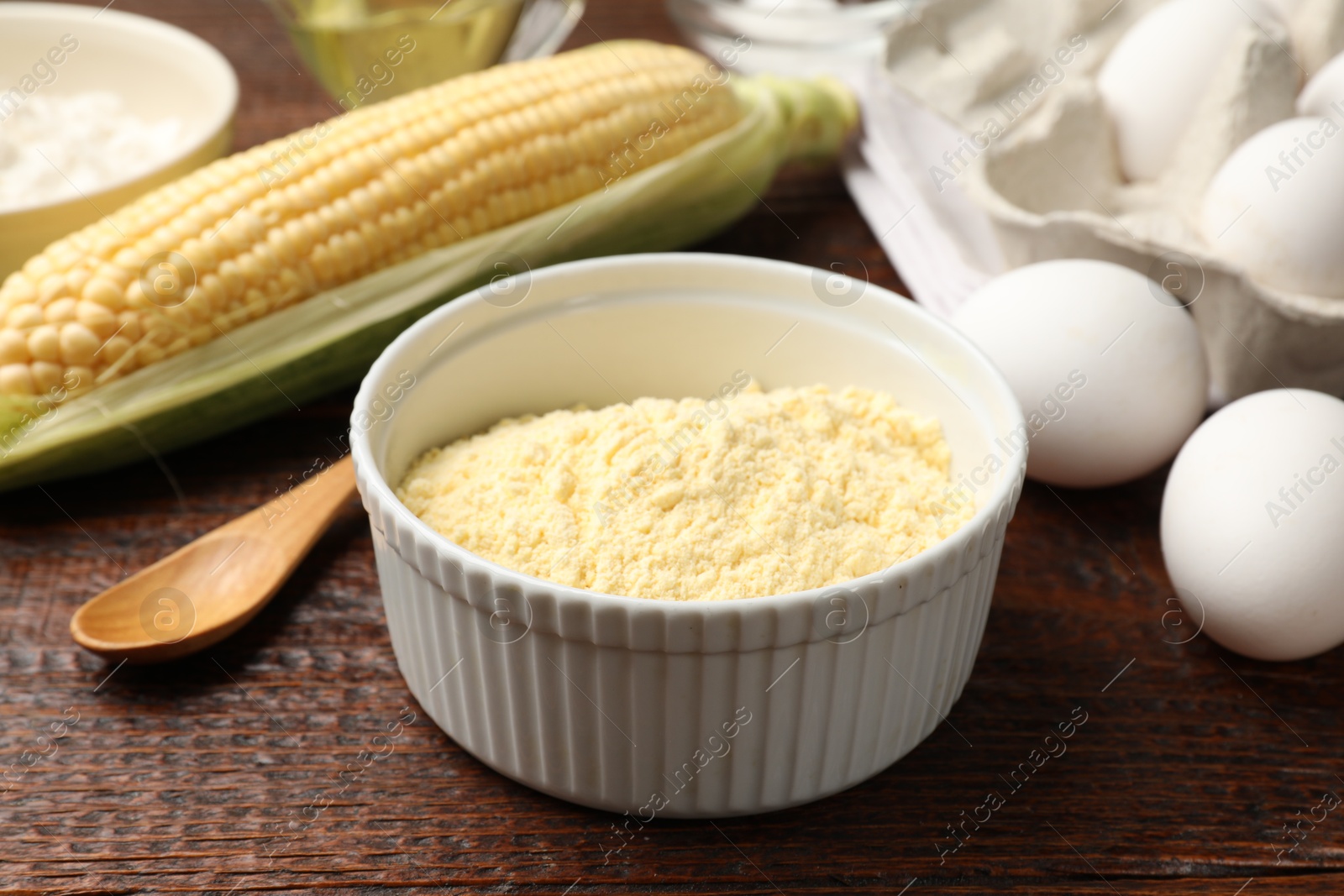 Photo of Different ingredients for corn bread. Corn flour, cob and eggs on wooden table, closeup
