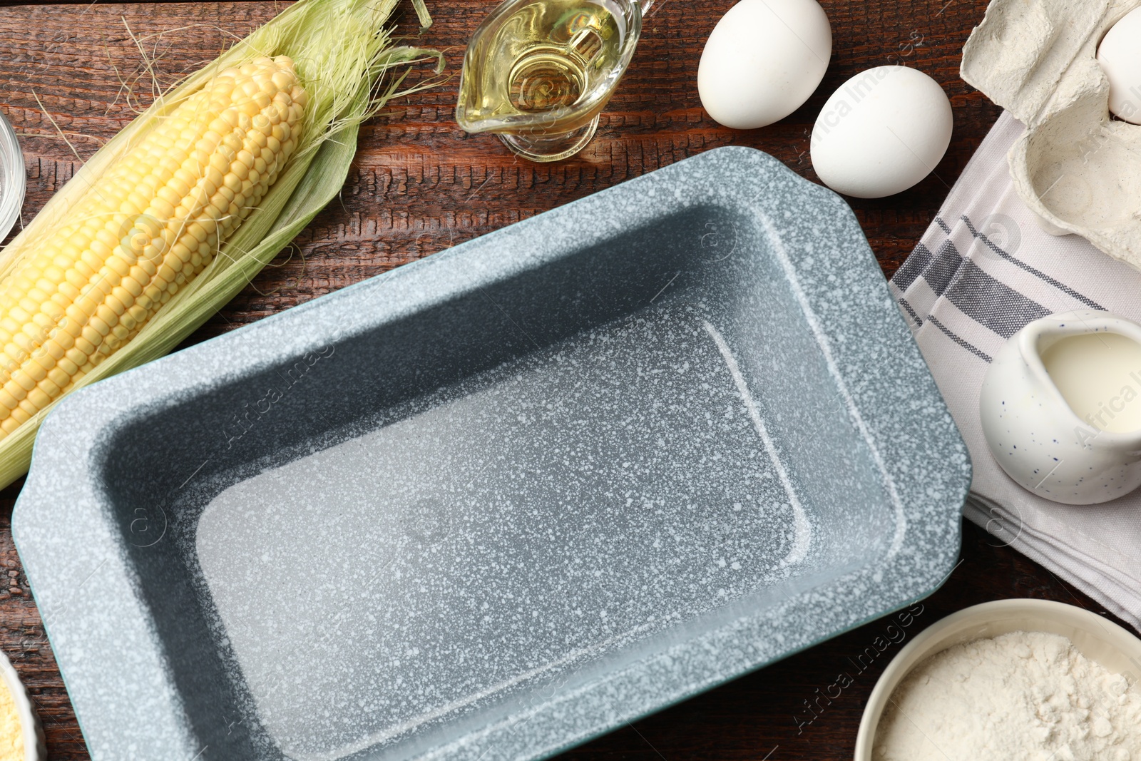 Photo of Baking dish and different ingredients for corn bread on wooden table, flat lay. Space for text
