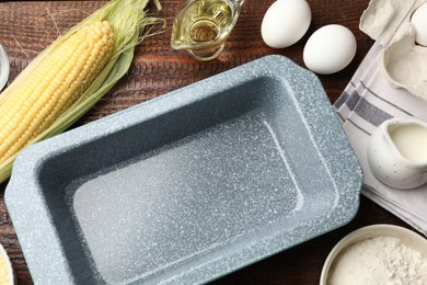 Photo of Baking dish and different ingredients for corn bread on wooden table, flat lay. Space for text