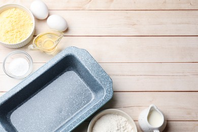 Photo of Baking dish and different ingredients for corn bread on light wooden table, flat lay. Space for text