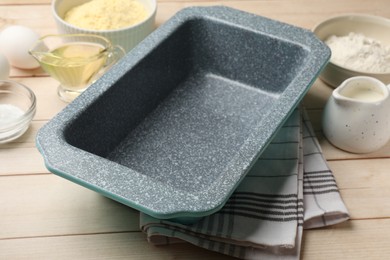 Photo of Baking dish and different ingredients for corn bread on light wooden table, closeup