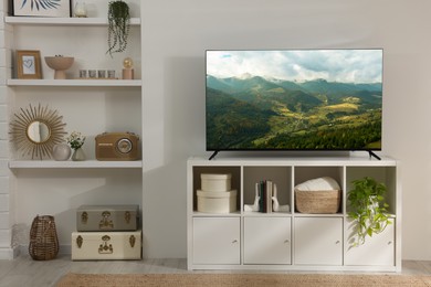 Image of TV set on console in room. Mountain landscape on screen