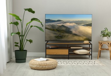 Image of TV set on console in room. Mountain landscape on screen