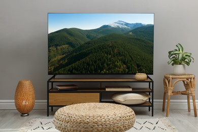Image of TV set on console in room. Mountain landscape on screen