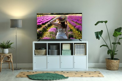 Image of TV set on console in room. Woman in lavender field on screen