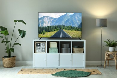 Image of TV set on console in room. Mountain landscape on screen