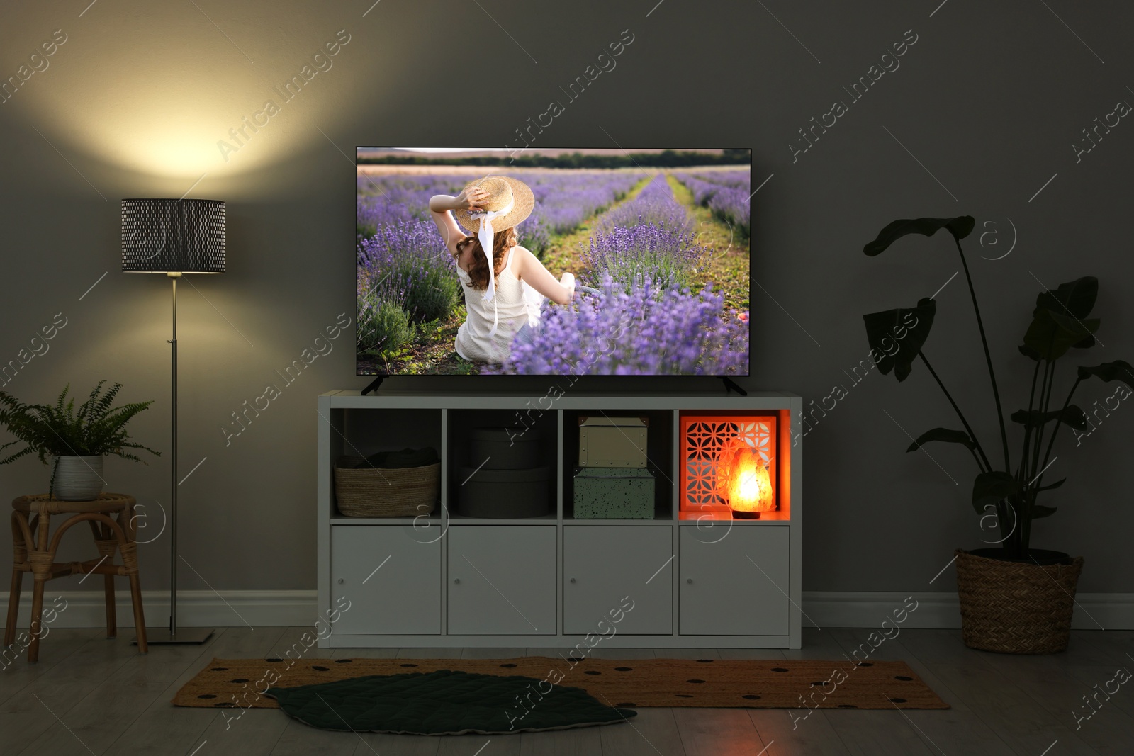 Image of TV set on console in room. Woman in lavender field on screen