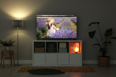 Image of TV set on console in room. Woman in lavender field on screen