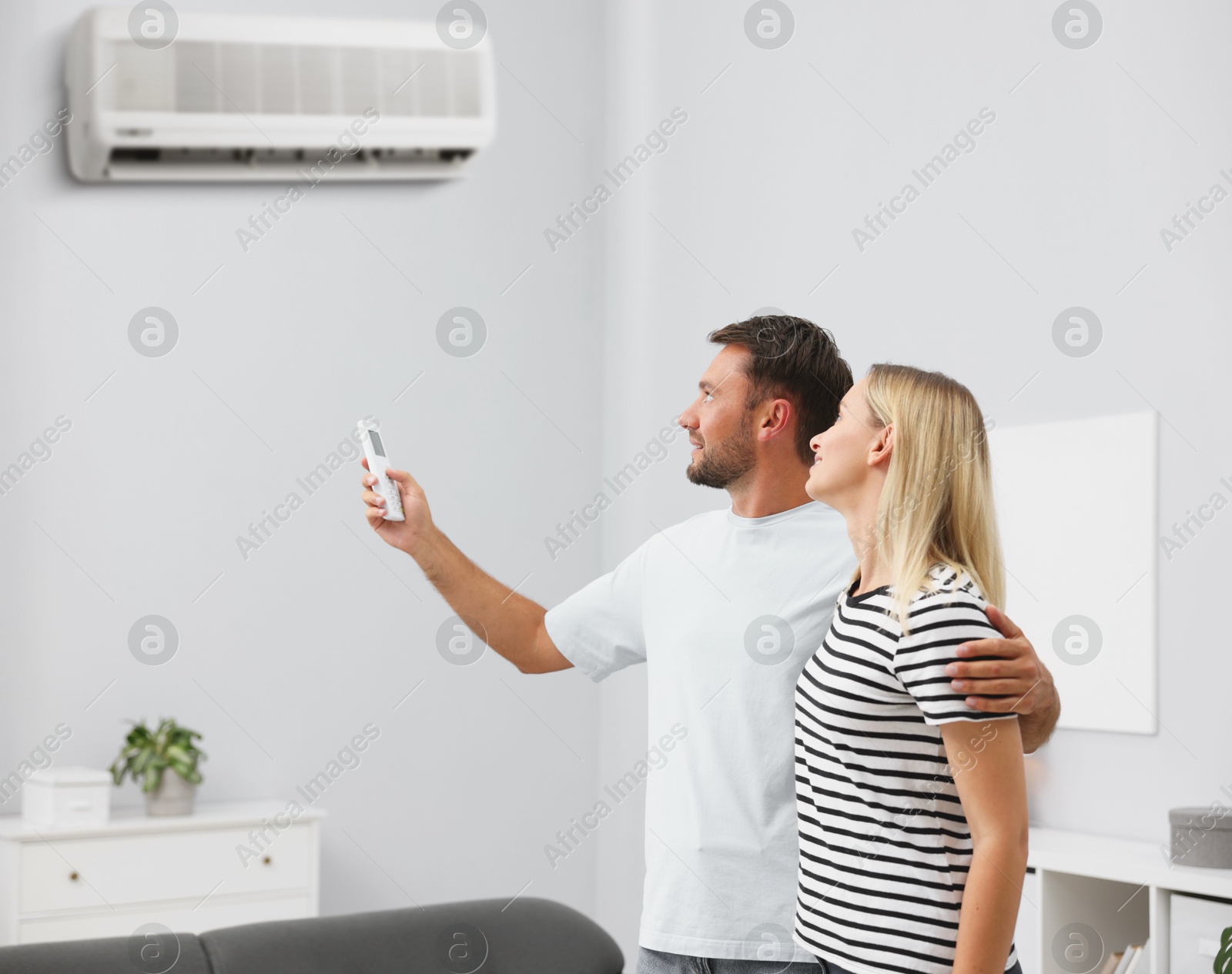 Image of Couple using remote to control air conditioner at home