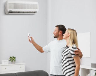 Image of Couple using remote to control air conditioner at home