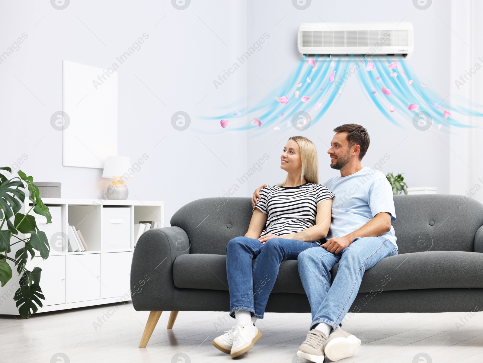 Image of Happy couple on sofa in room with air conditioner