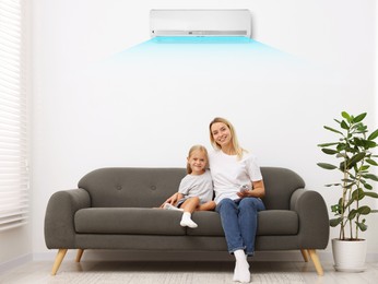 Image of Mother using remote to control air conditioner and hugging her daughter on sofa at home