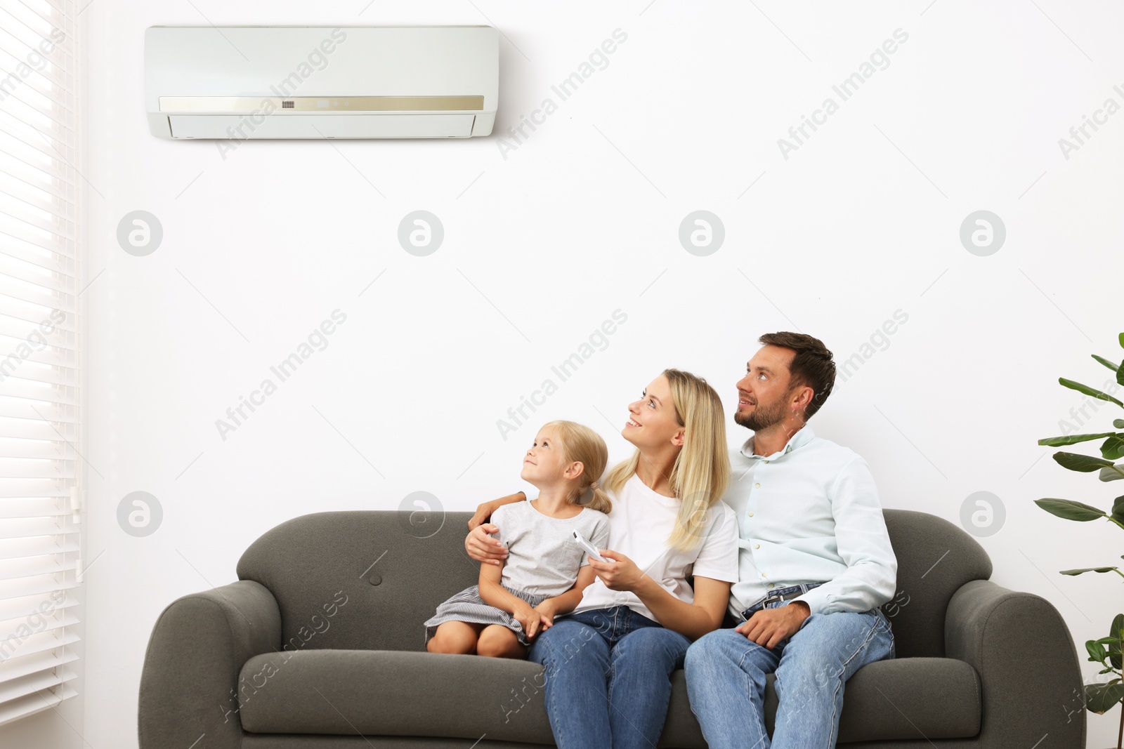 Image of Happy family on sofa in room with air conditioner
