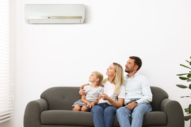 Image of Happy family on sofa in room with air conditioner