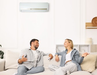 Image of Couple spending time together on sofa in room with air conditioner