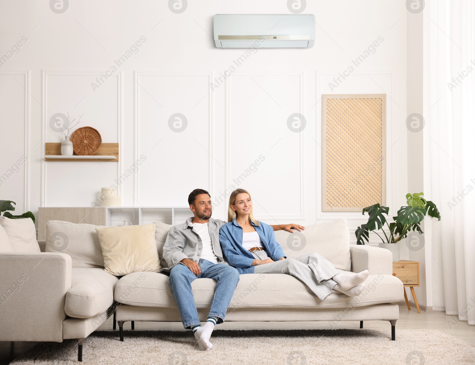 Couple resting on sofa in room with air conditioner Image of Couple resting on sofa in room with air conditioner