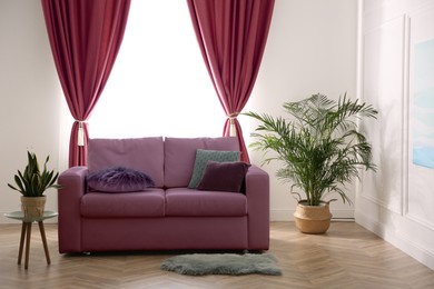 Image of Living room with dark magenta sofa and houseplants. Interior design