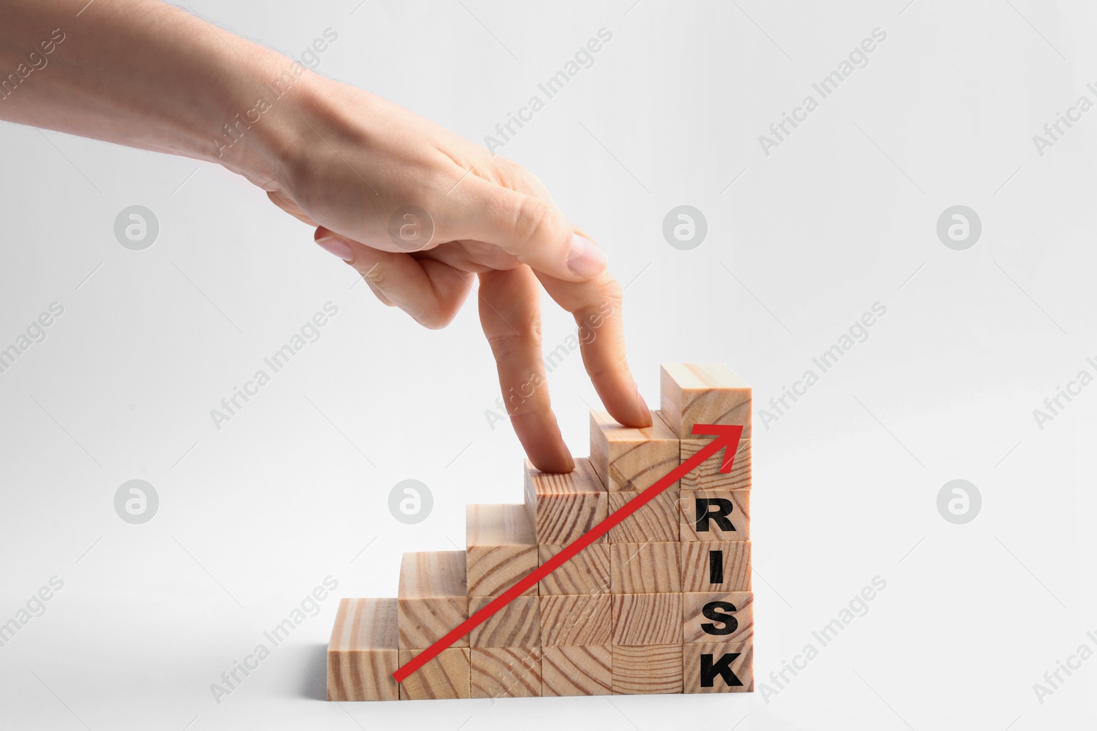 Image of Woman stepping up with fingers on wooden cubes with arrow and word Risk against white background, closeup
