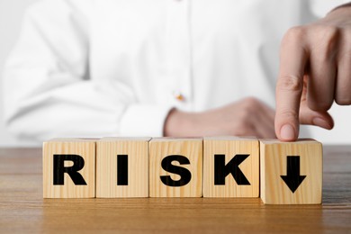Image of Business risk. Woman touching wooden cube with arrow at table, closeup