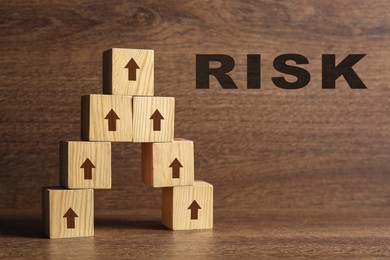 Image of Risk. Pyramid of wooden cubes with arrows on table