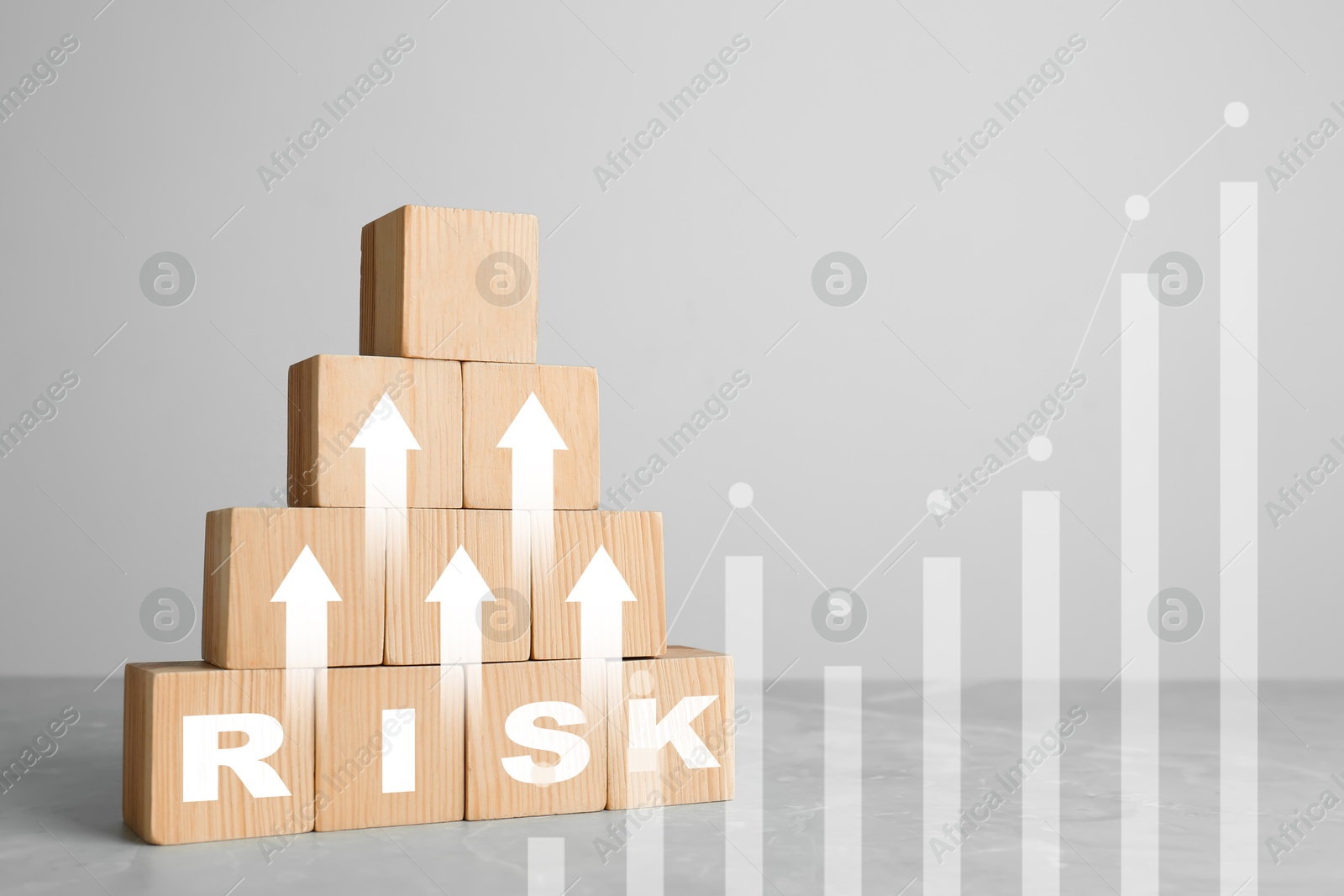 Image of Pyramid of wooden cubes with word Risk and arrows on table