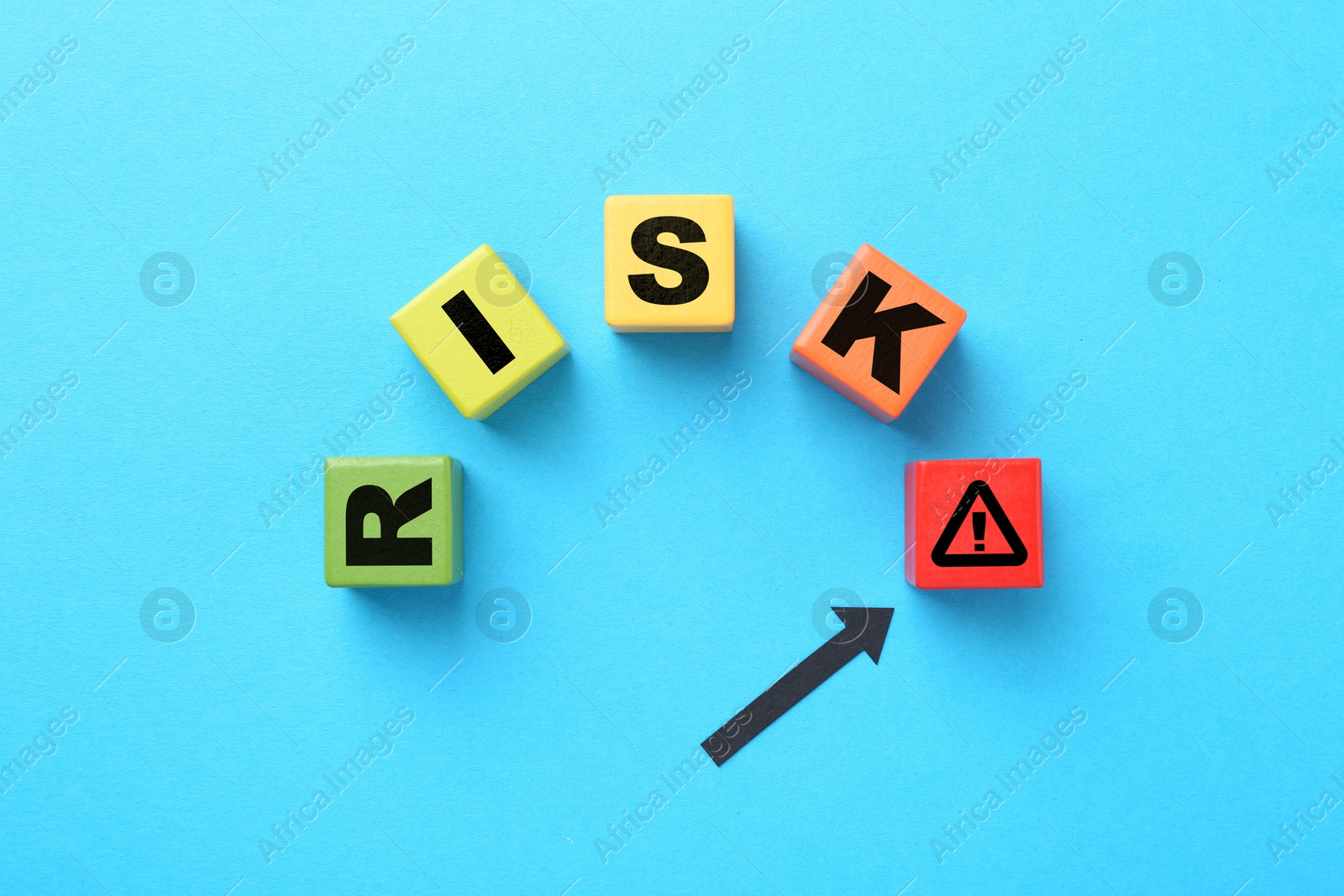 Image of Word Risk of wooden cubes with letters on light blue background, top view. Arrow pointing at warning sign