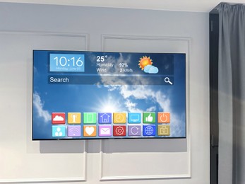 Image of TV set on wall in room. Menu with icons and information on display