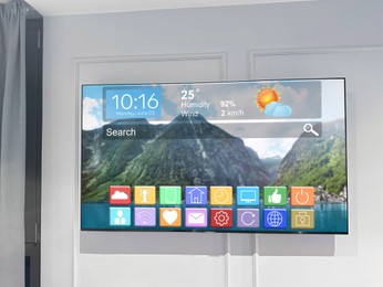 Image of TV set on wall in room. Menu with icons and information on display