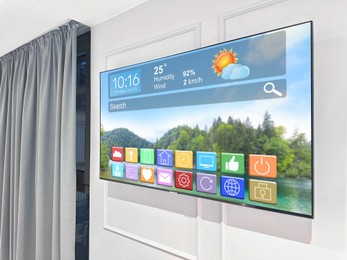 Image of TV set on wall in room. Menu with icons and information on display