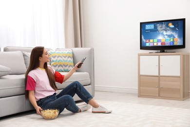 Image of Woman watching TV at home. Menu with icons and information on display