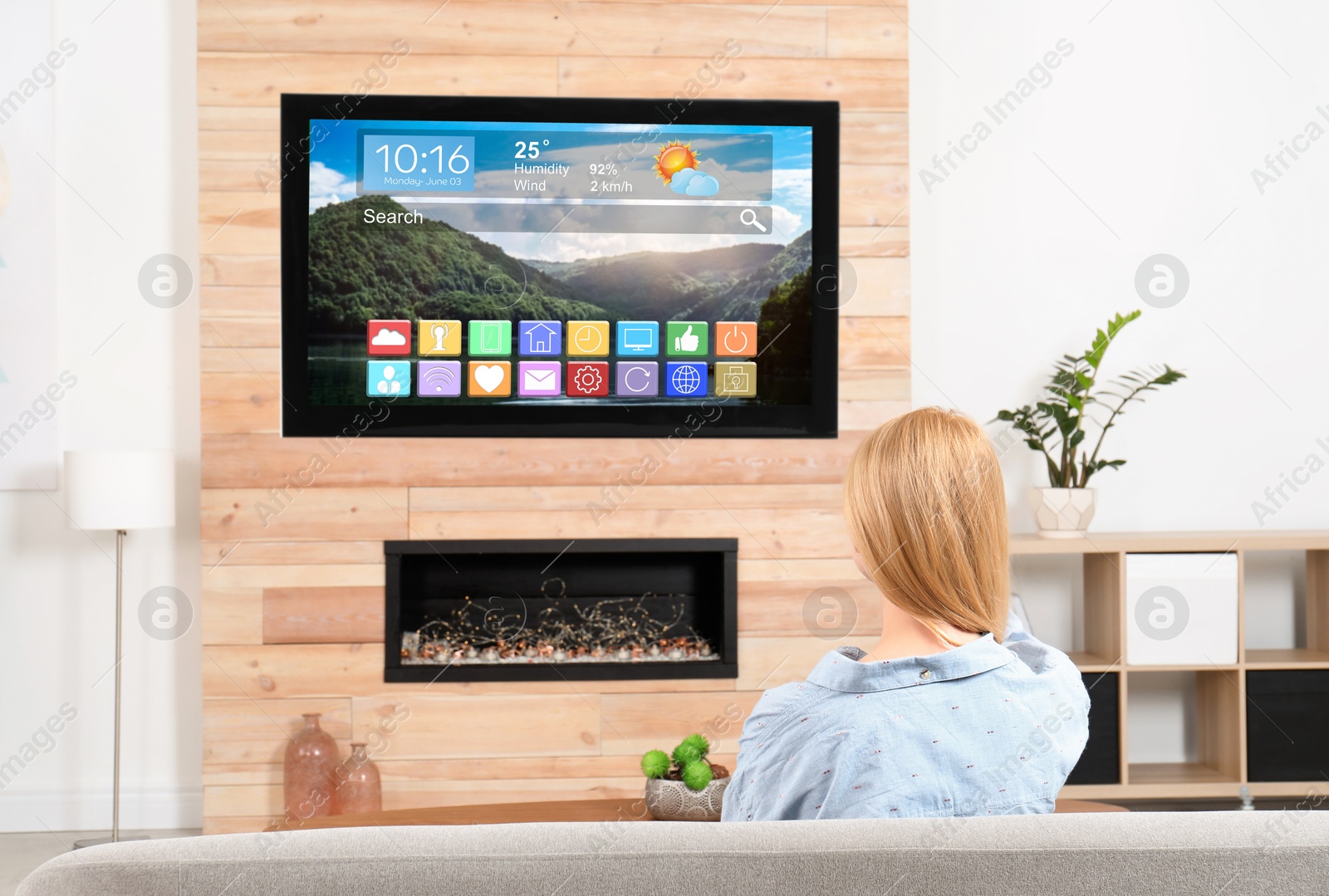 Image of Woman watching TV at home, back view. Menu with icons and information on display
