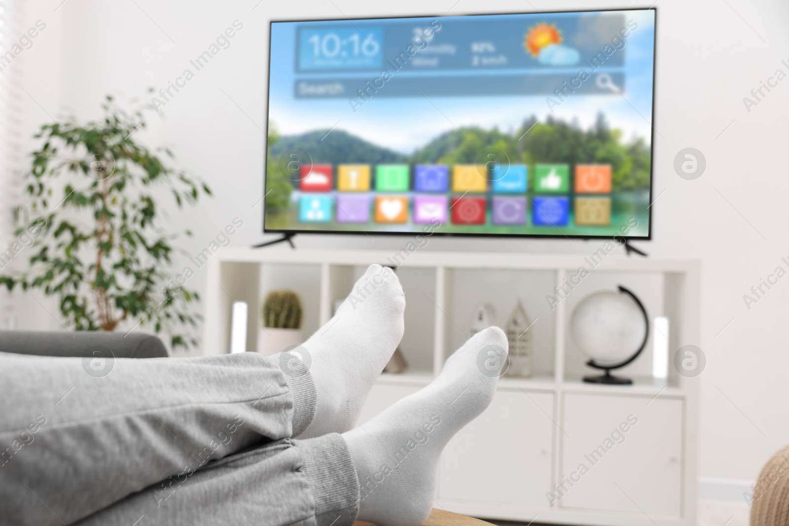Man watching TV at home, closeup. Menu with icons and information on display Image of Man watching TV at home, closeup. Menu with icons and information on display