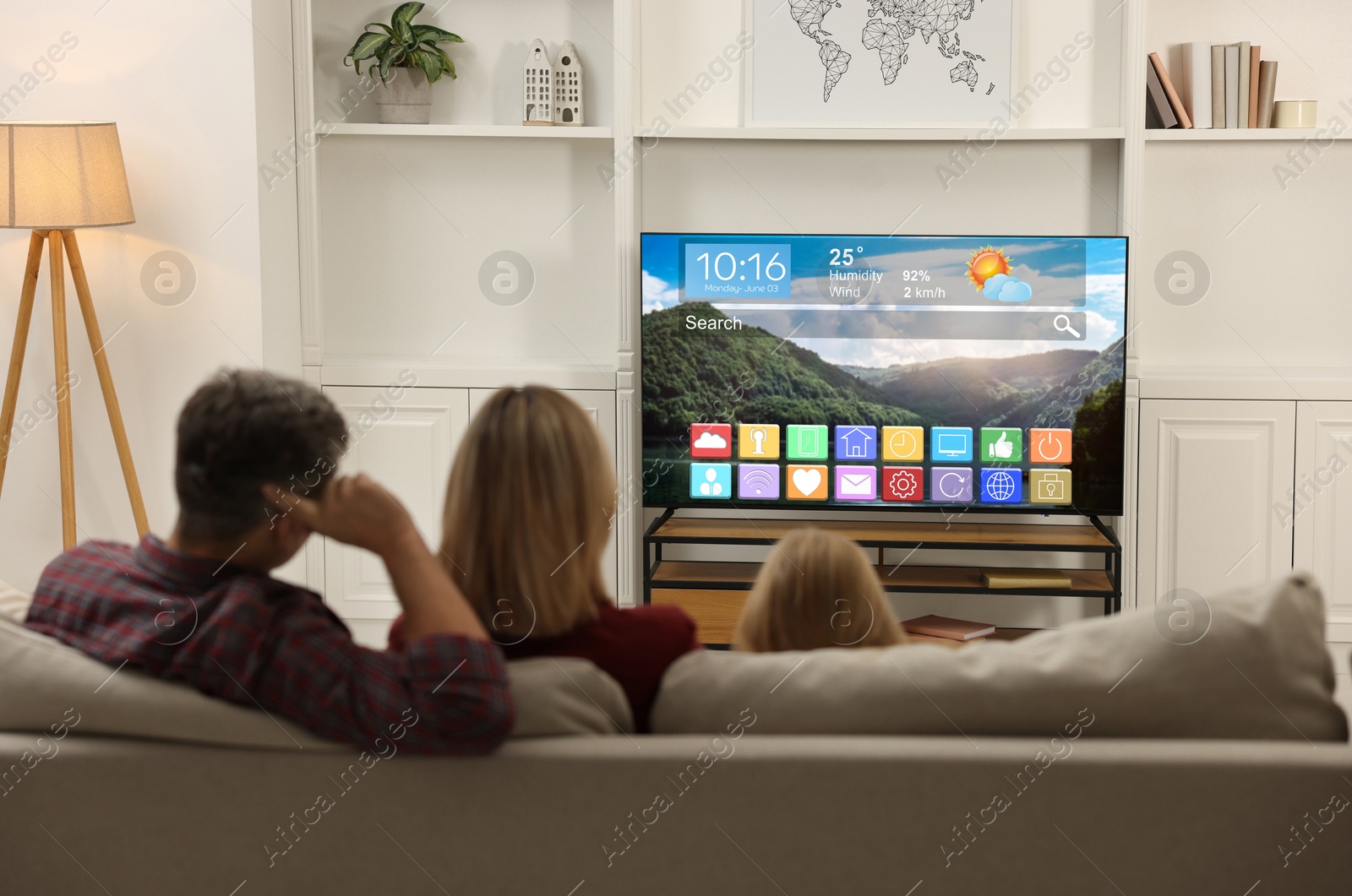 Image of Family watching TV at home, back view. Menu with icons and information on display