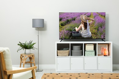 Image of TV set on console in room. Woman in lavender field on screen