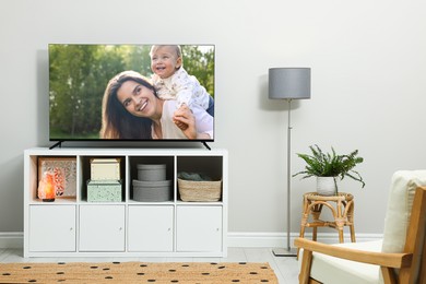 Image of TV set on console in room. Mother with her child on screen