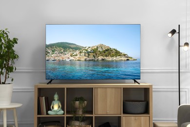 Image of TV set on console in room. Landscape on screen
