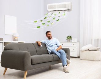 Image of Man with air conditioner remote control on sofa at home