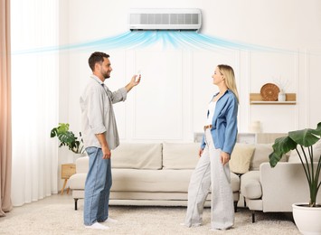 Image of Couple at home. Man using remote to control air conditioner