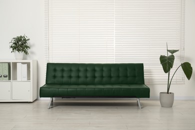Image of Living room with dark green sofa and houseplants. Interior design