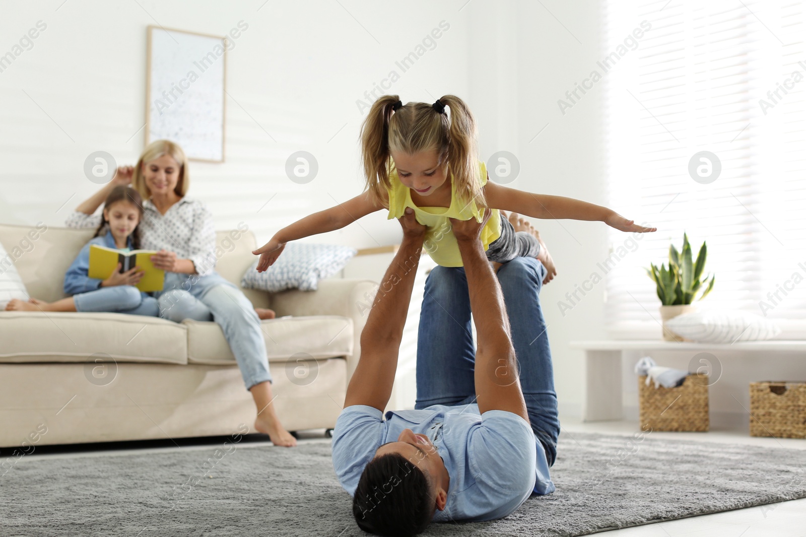 Photo of Happy father playing with his daughter on floor at home