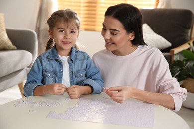 Photo of Happy mother and her daughter playing with puzzles at home