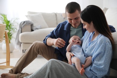Photo of Happy family with cute baby near sofa at home